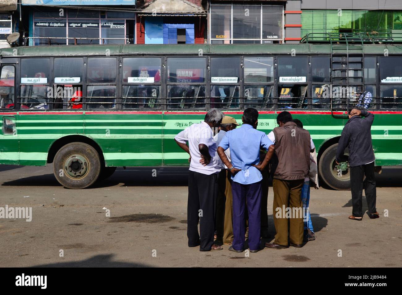 Sultan Bathery, India - January, 2017: Crowd of older Hindu men stands near old green passenger bus. Group of Indian men talking. Typical Indian bus Stock Photo