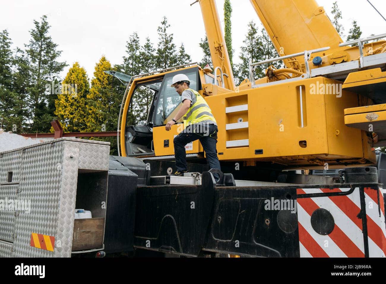 Operator climbing on Construction crane lifting heavy freight. Modern mobile transportation technologies help building house. Real estate professional Stock Photo