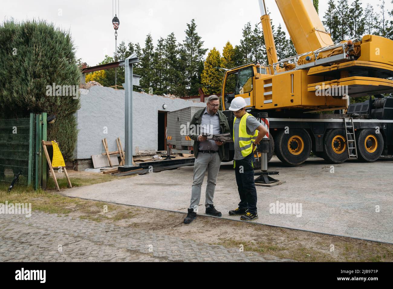 Foreman and customer or client agree about future building work on construction site. Man looking in paper, architect discussing project with builder Stock Photo