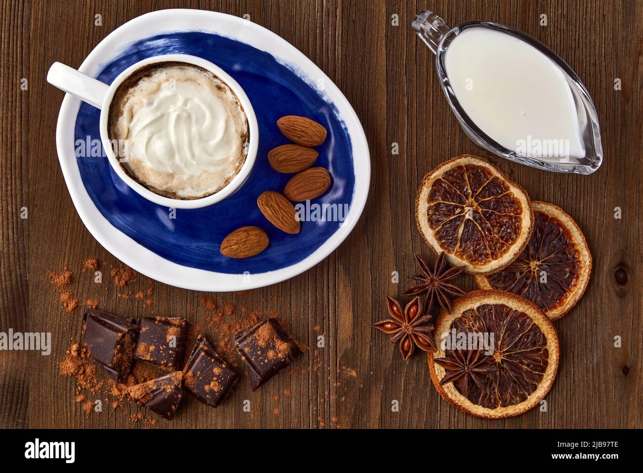 Blue cup of Viennese coffee with cream, chocolate and spices on a dark wooden table. View from above Stock Photo