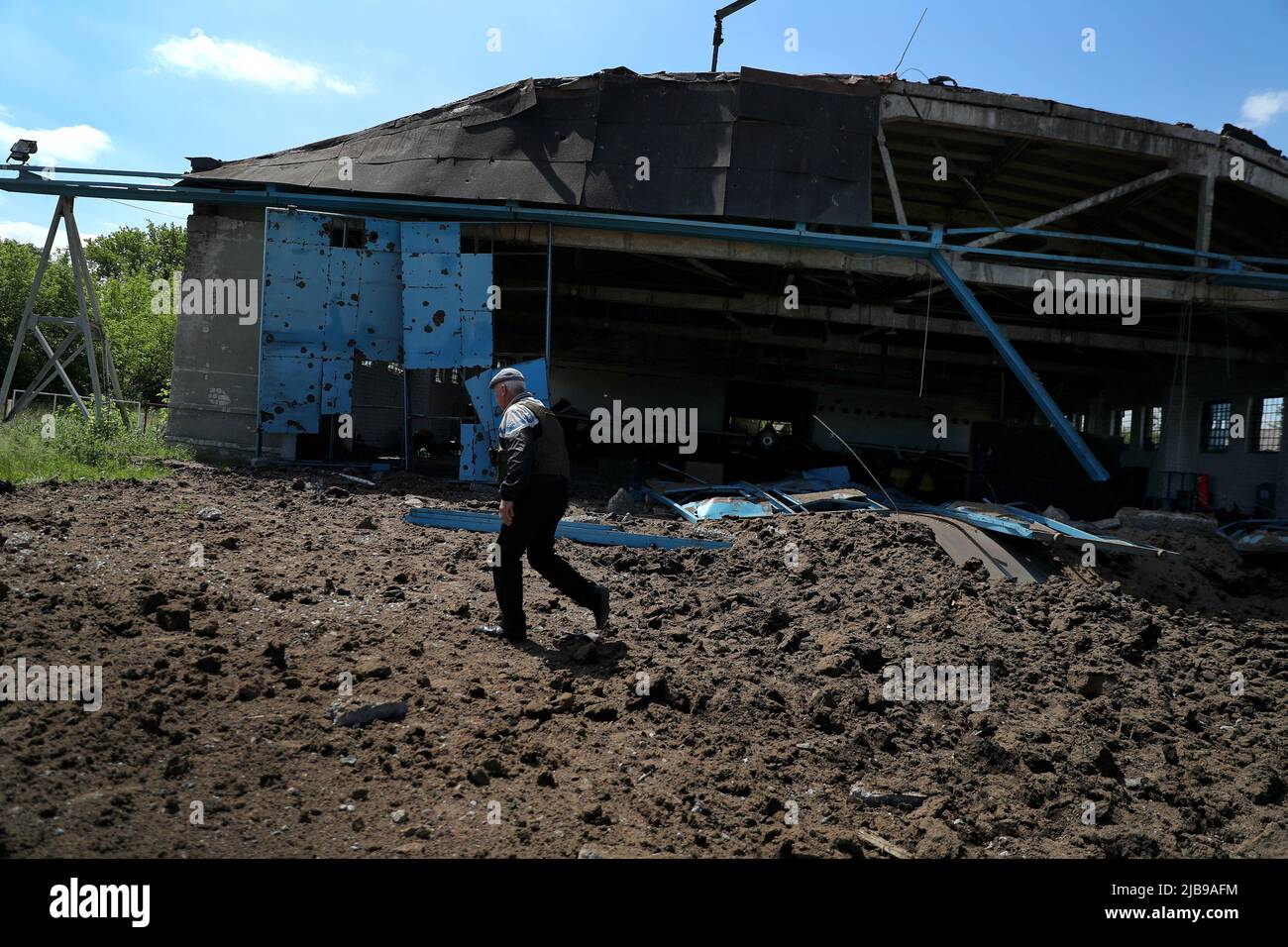 A man walks past a hangar at a damaged private airfield following a military strike, amid Russia's attack on Ukraine, on the outskirts of Kharkiv, Ukraine June 4, 2022. REUTERS/Ivan Alvarado Stock Photo