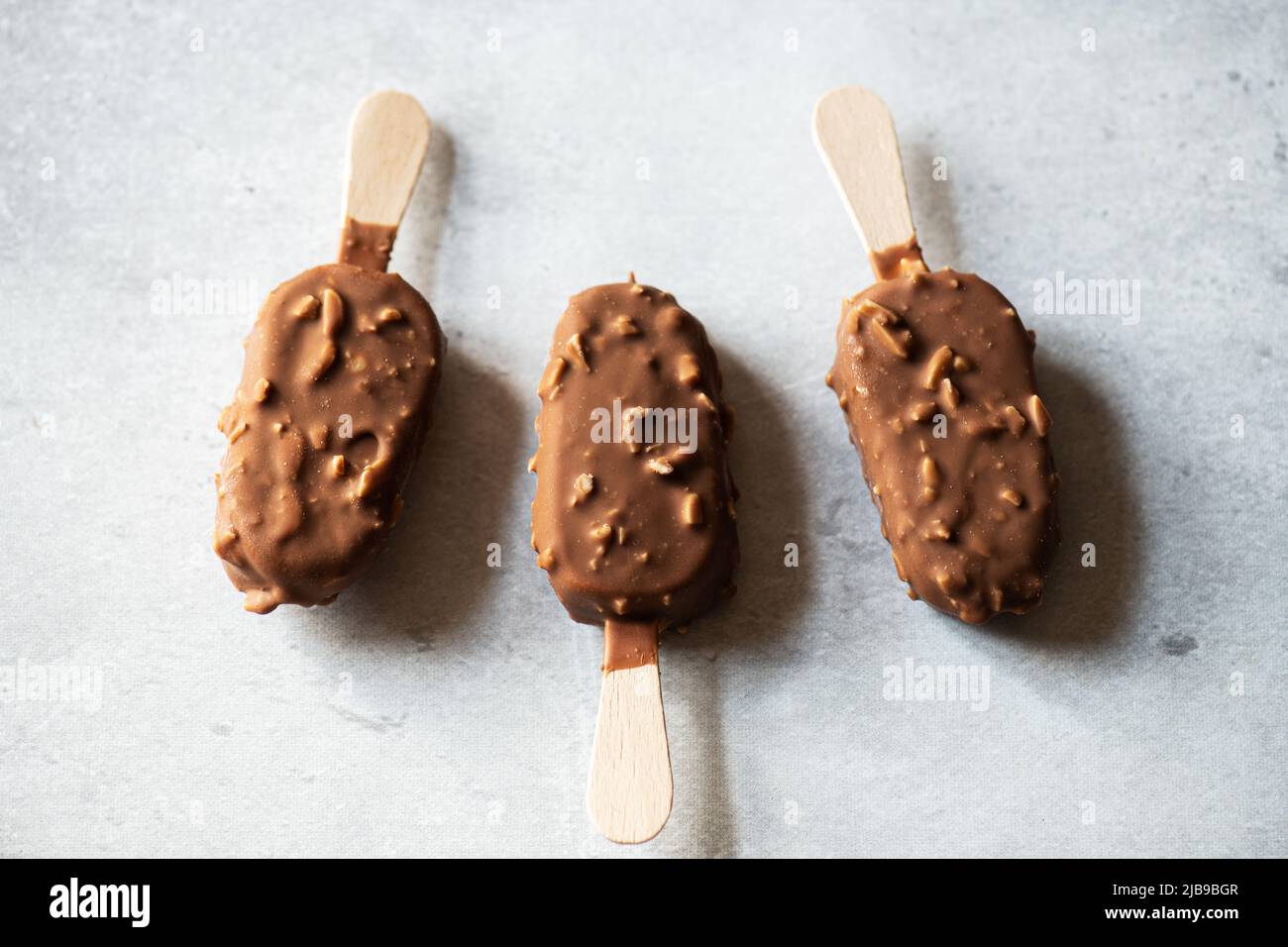 https://c8.alamy.com/comp/2JB9BGR/chocolate-almond-ice-cream-on-a-wooden-stick-on-a-gray-background-top-view-2JB9BGR.jpg