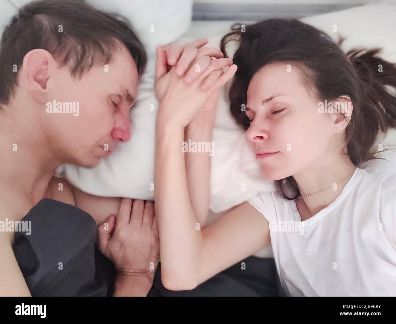 Loving married couple sleeping and holding hands - eyes closed Stock Photo