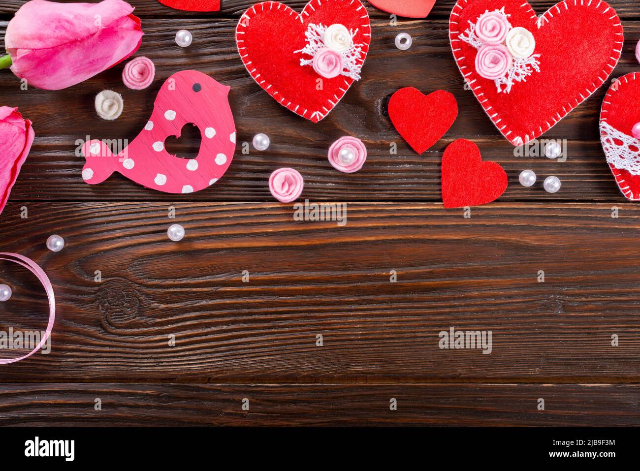 Sewed handmade fabric hearts tulips and ribbon for valentine day on dark wooden background with copy space Stock Photo