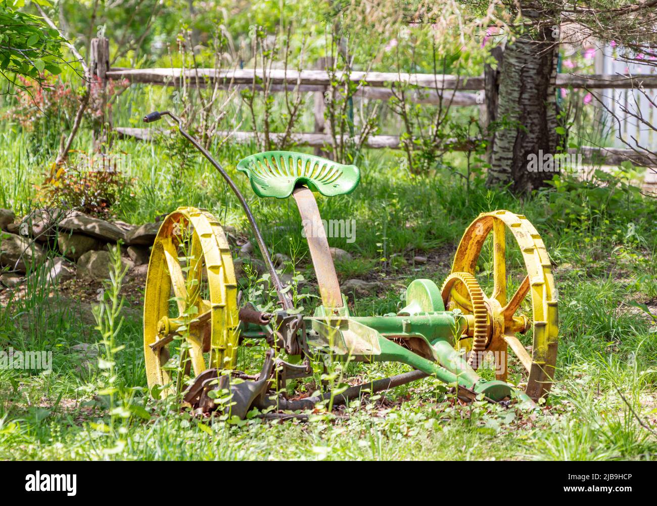 Old farm implement in an overgrown yard Stock Photo