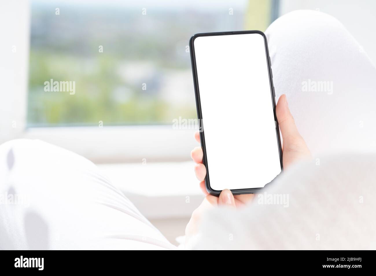 woman user customer hold cellphone mockup with white screen in hand. Use mobile shopping app, check social media news, texting mobile sms order food d Stock Photo