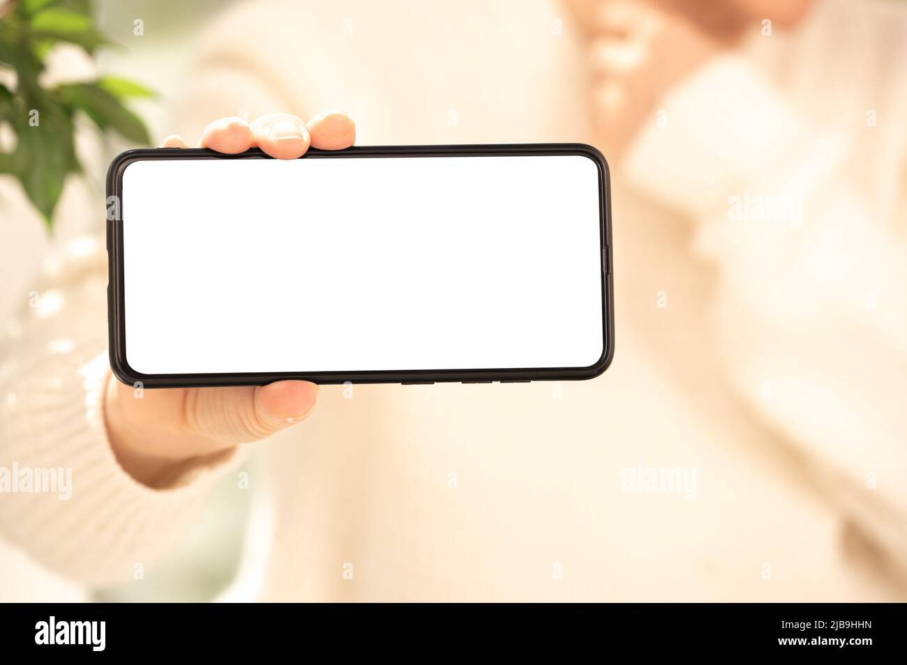 Cellphone mockup. woman in white clothes shows blank white cell phone screen in horizontal position. woman hand holding and showing black mobile smart Stock Photo