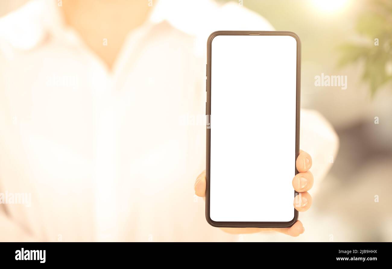 Cellphone mockup. woman in white clothes shows blank white cell phone screen. woman hand holding and showing black mobile smart phone with blank white Stock Photo