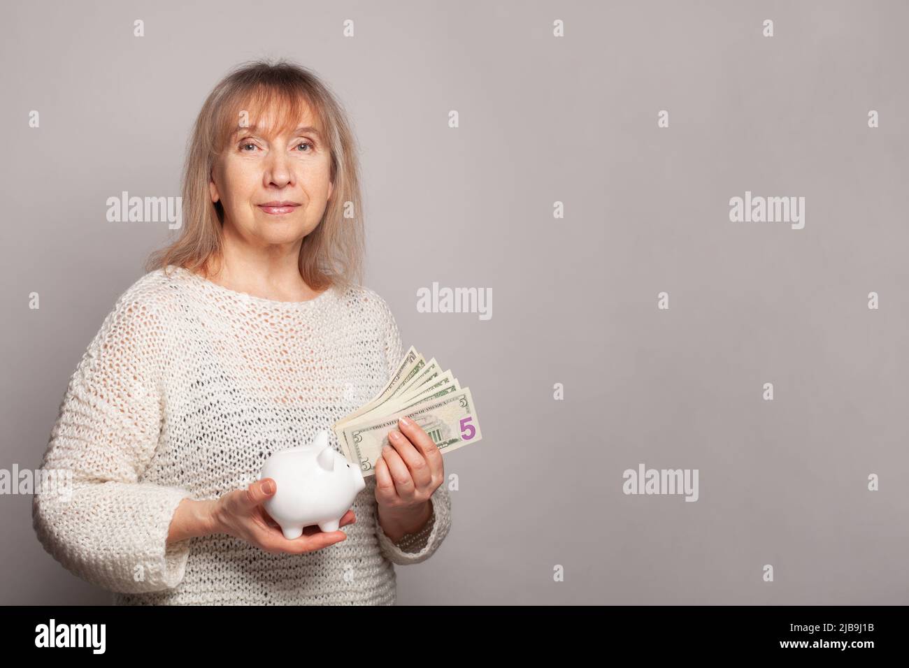 Happy smiling senior woman holding us dollar money banknotes and piggy ...