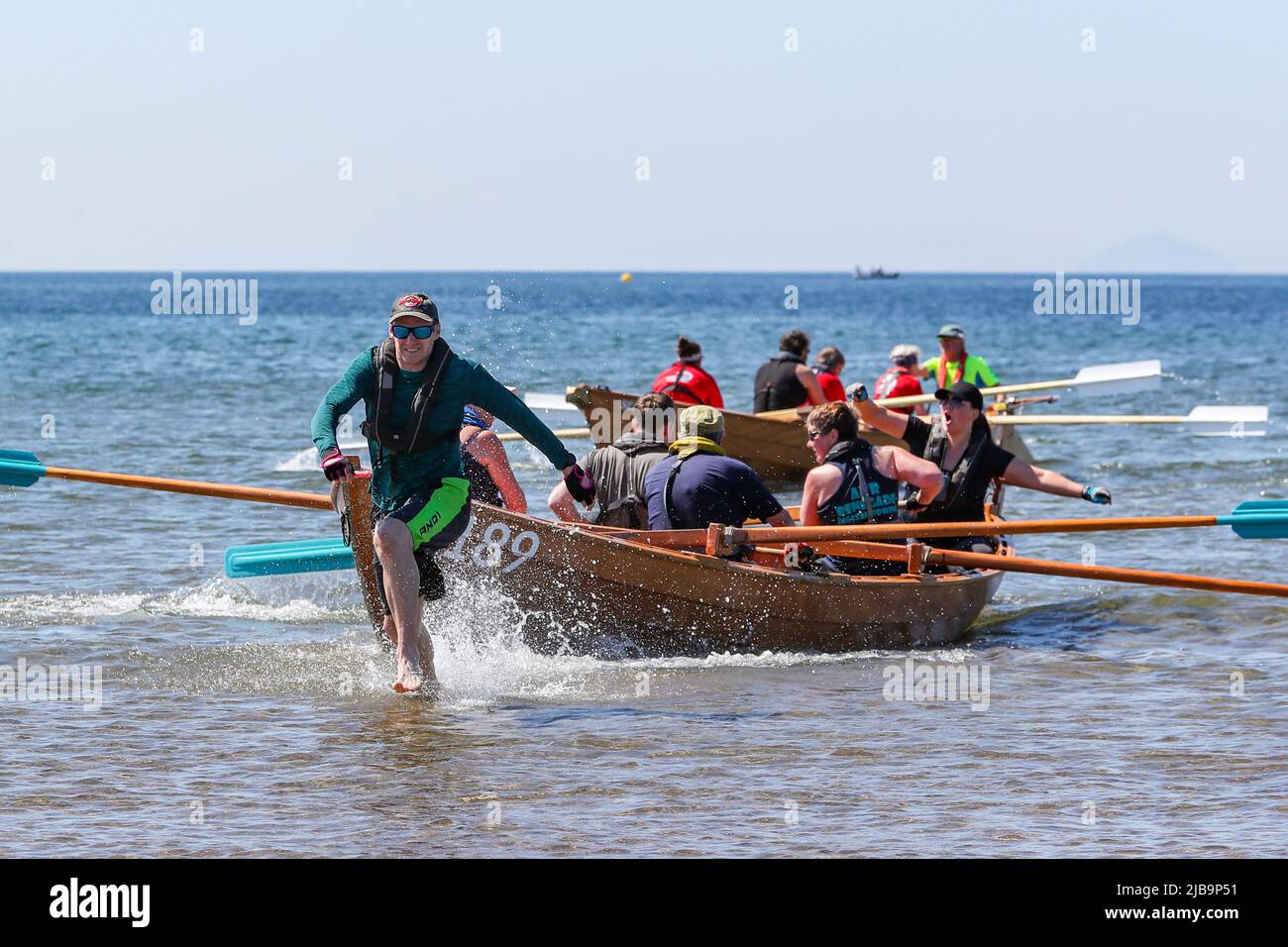Troon, UK. 04th June, 2022. 04 June 2022. Troon, UK. Troon Coastal Rowing Club (TCRC) held its annual regatta on the Firth of Clyde sailing from south beach Troon, Ayrshire, UK. The small boats are traditional, hand crafted, wooden, 4 crew, fishing skiffs, based on a 300 year old design. The race requires the competitors to row a set course of not less than 2 kilometres, leaving from the shore and on return, a team member has to take a stick of Troon rock (confectionery} and run to the finish line with it. The event attracted competitors from various coastal rowing clubs across Scotland Stock Photo