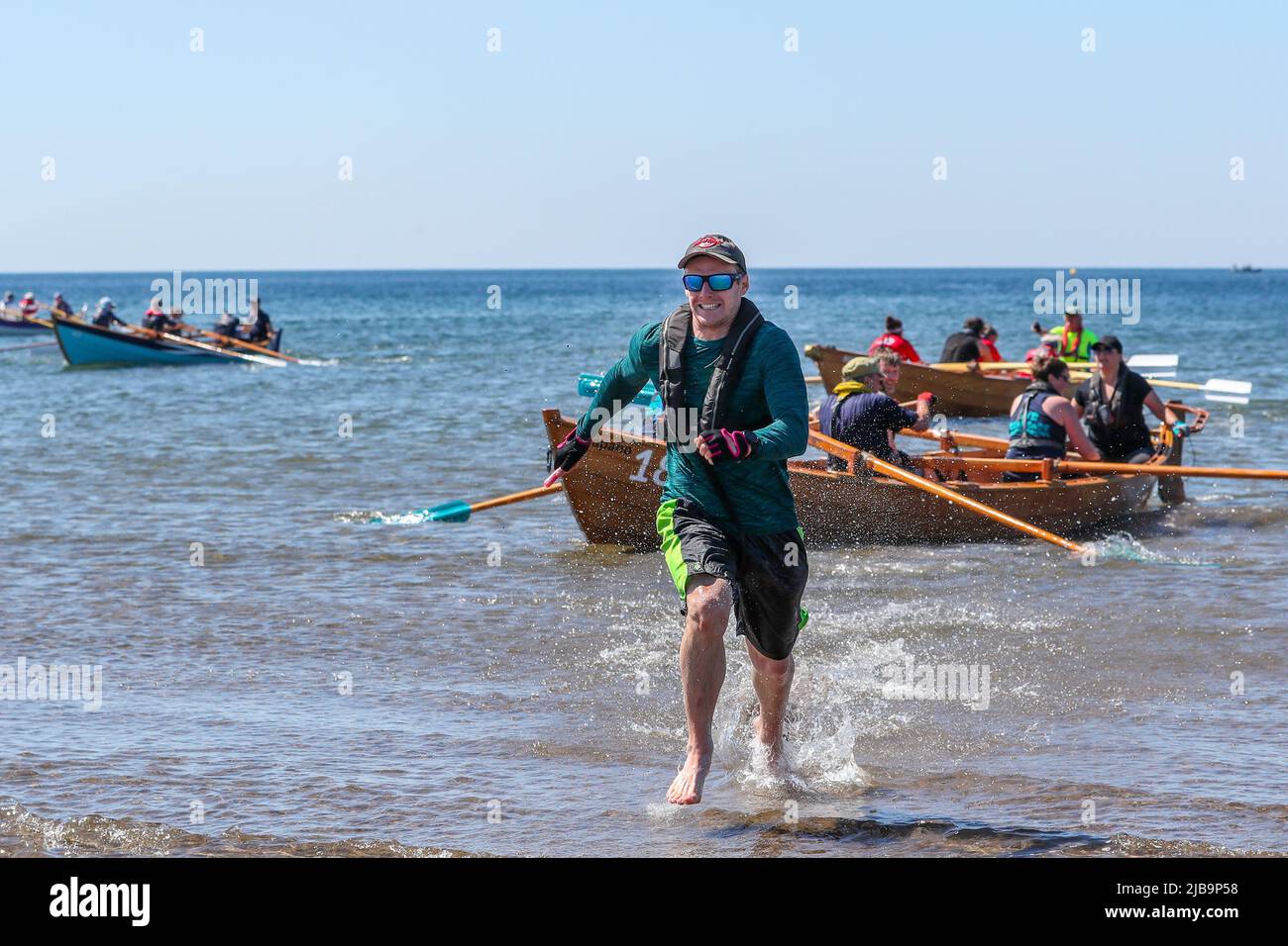 Troon, UK. 04th June, 2022. 04 June 2022. Troon, UK. Troon Coastal Rowing Club (TCRC) held its annual regatta on the Firth of Clyde sailing from south beach Troon, Ayrshire, UK. The small boats are traditional, hand crafted, wooden, 4 crew, fishing skiffs, based on a 300 year old design. The race requires the competitors to row a set course of not less than 2 kilometres, leaving from the shore and on return, a team member has to take a stick of Troon rock (confectionery} and run to the finish line with it. The event attracted competitors from various coastal rowing clubs across Scotland Stock Photo