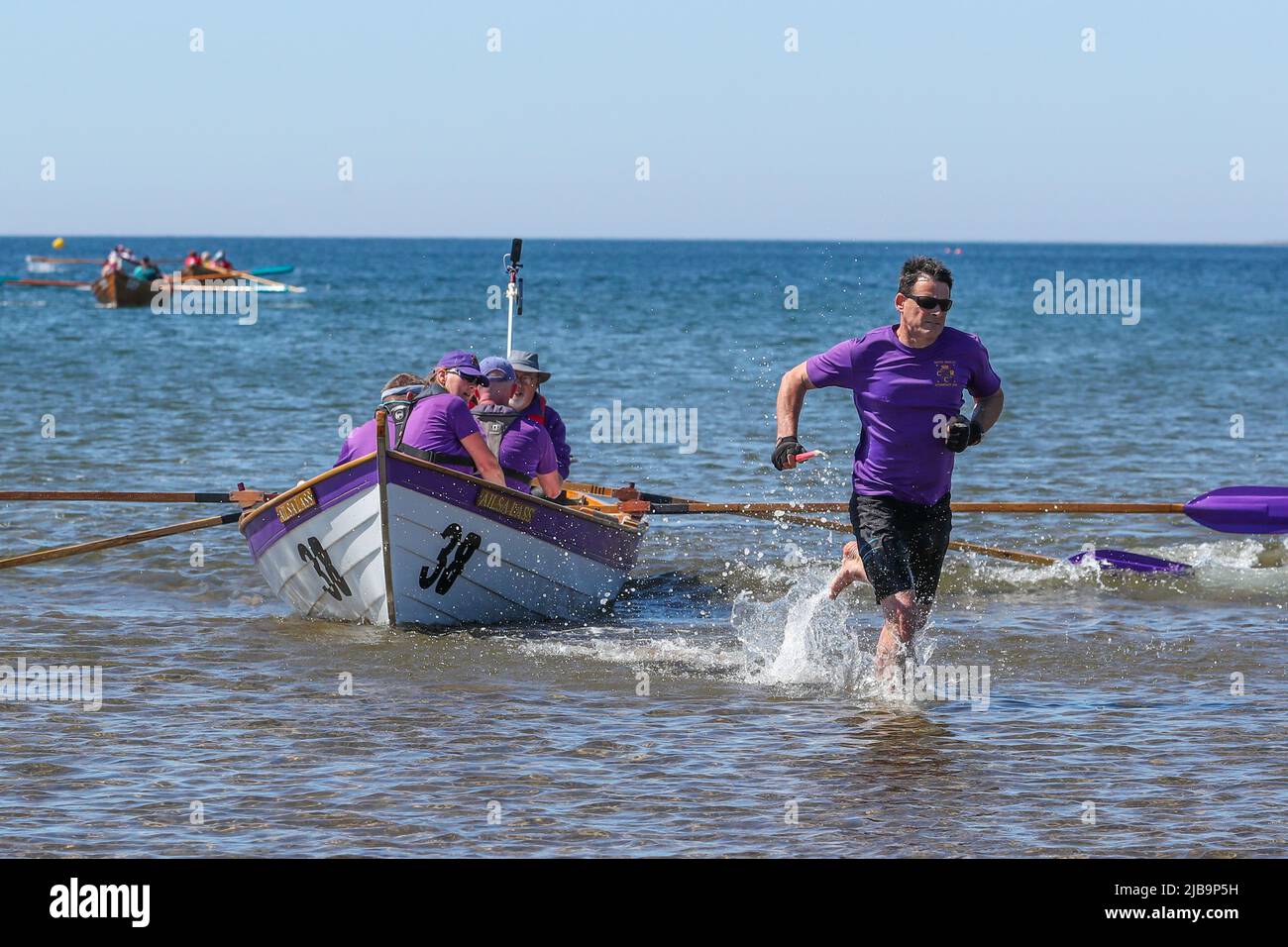 Troon, UK. 04th June, 2022. 04 June 2022. Troon, UK. Troon Coastal Rowing Club (TCRC) held its annual regatta on the Firth of Clyde sailing from south beach Troon, Ayrshire, UK. The small boats are traditional, hand crafted, wooden, 4 crew, fishing skiffs, based on a 300 year old design. The race requires the competitors to row a set course of not less than 2 kilometres, leaving from the shore and on return, a team member has to take a stick of Troon rock (confectionery} and run to the finish line with it. The event attracted competitors from various coastal rowing clubs across Scotland Stock Photo