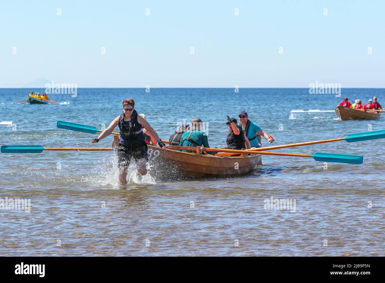 Troon, UK. 04th June, 2022. 04 June 2022. Troon, UK. Troon Coastal Rowing Club (TCRC) held its annual regatta on the Firth of Clyde sailing from south beach Troon, Ayrshire, UK. The small boats are traditional, hand crafted, wooden, 4 crew, fishing skiffs, based on a 300 year old design. The race requires the competitors to row a set course of not less than 2 kilometres, leaving from the shore and on return, a team member has to take a stick of Troon rock (confectionery} and run to the finish line with it. The event attracted competitors from various coastal rowing clubs across Scotland Stock Photo