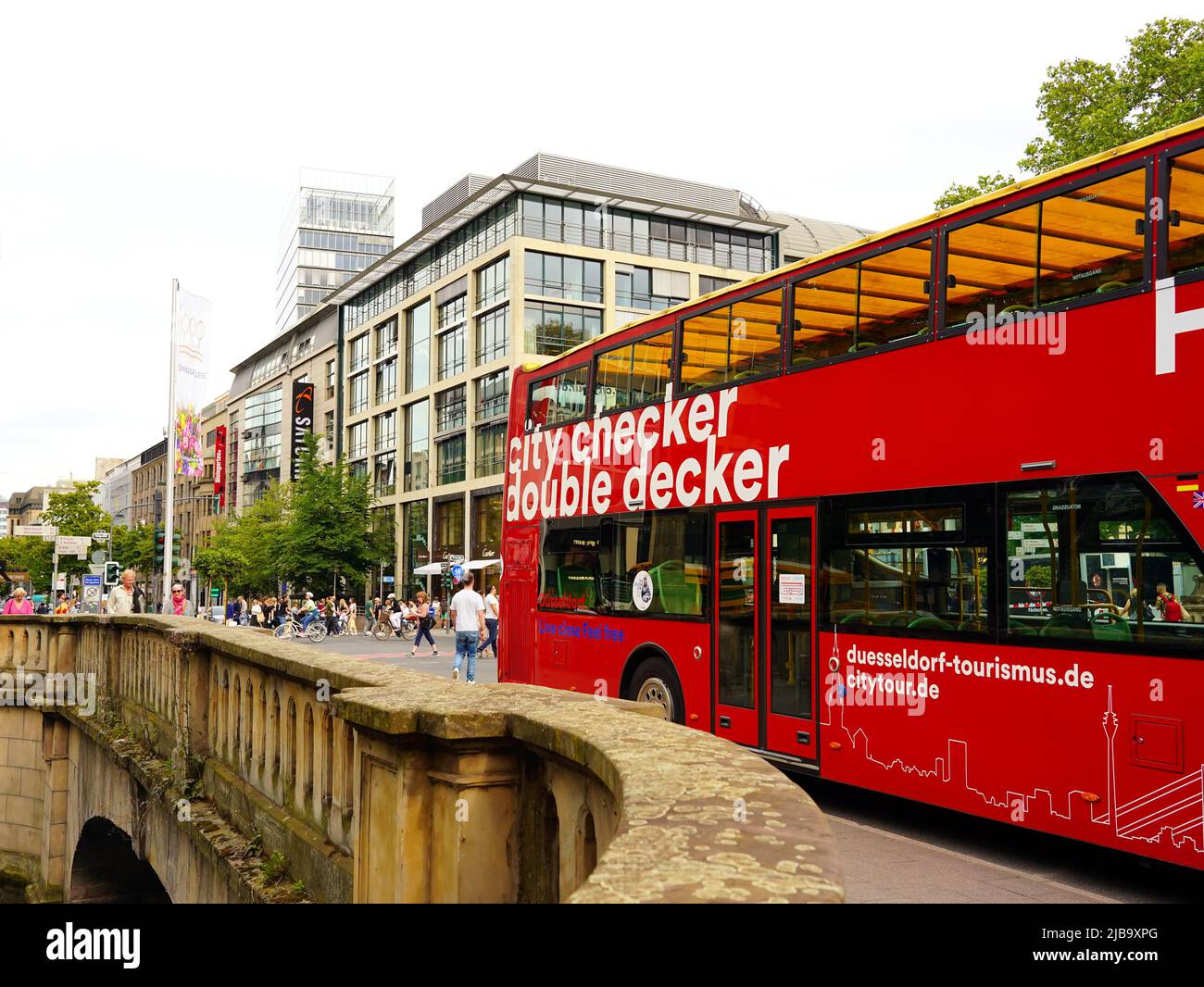 Red double decker city tour 'Hop on / Hop off' bus waiting at a stop on Königsallee in Düsseldorf/Germany. Stock Photo