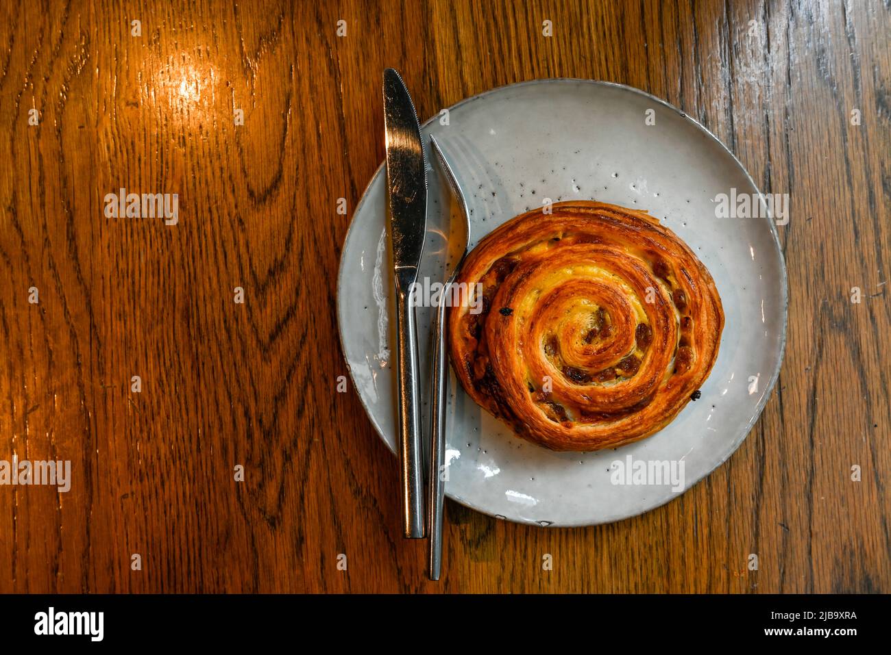 Swirl bun with raisins on a wooden table top view Stock Photo