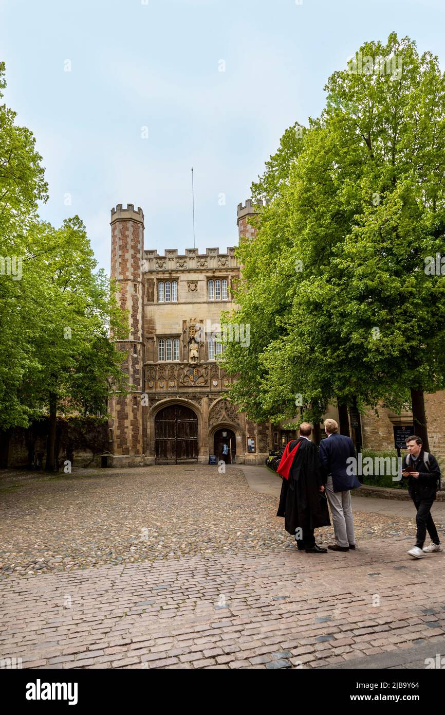 Student wearing a gown and red stole on Graduation Day at the main entrance of Trinity College, the Great Gate, Cambridge, Cambridgeshire, England, UK Stock Photo