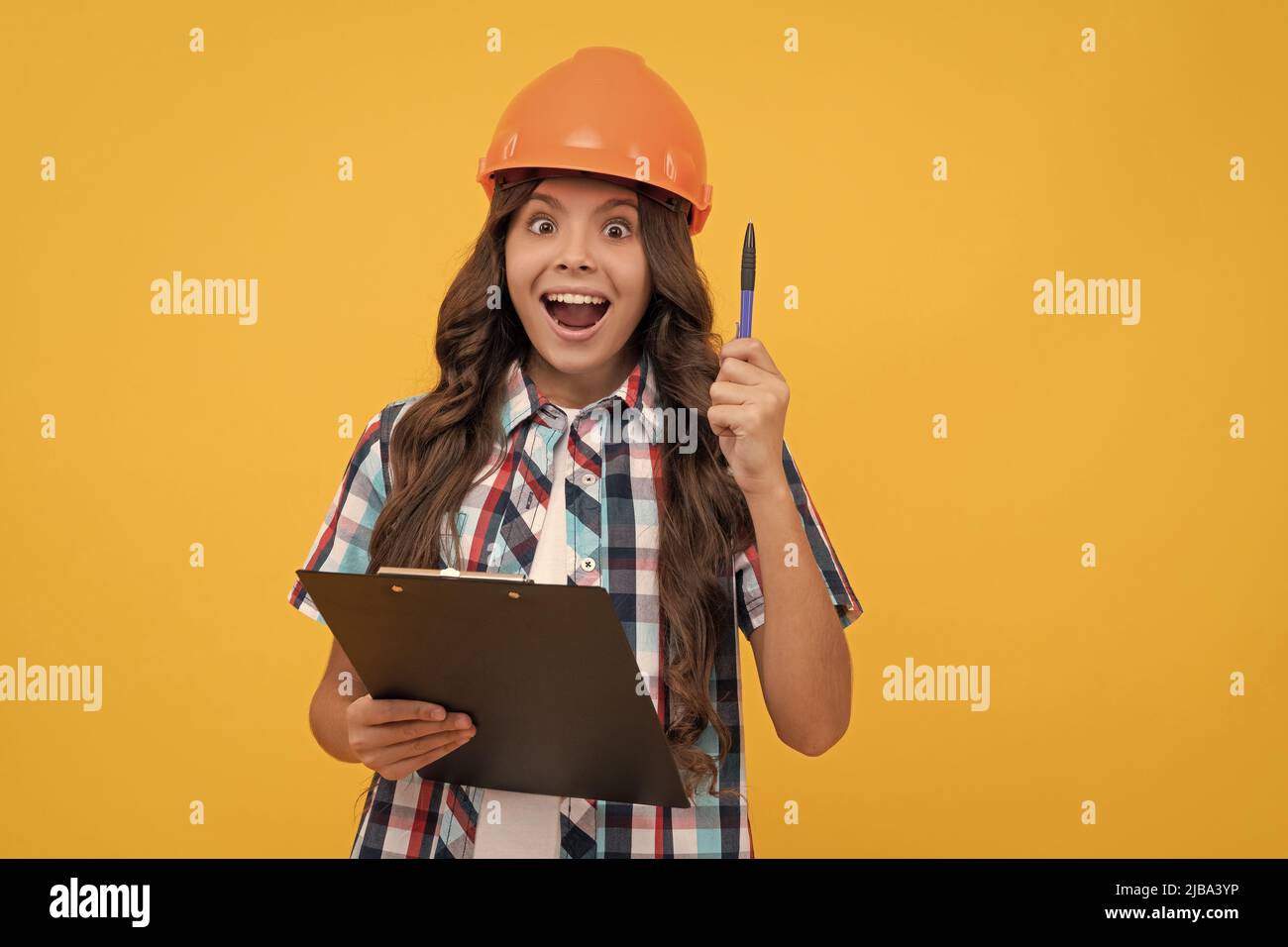 inspired girl in protective hard hat making notes. child in helmet read