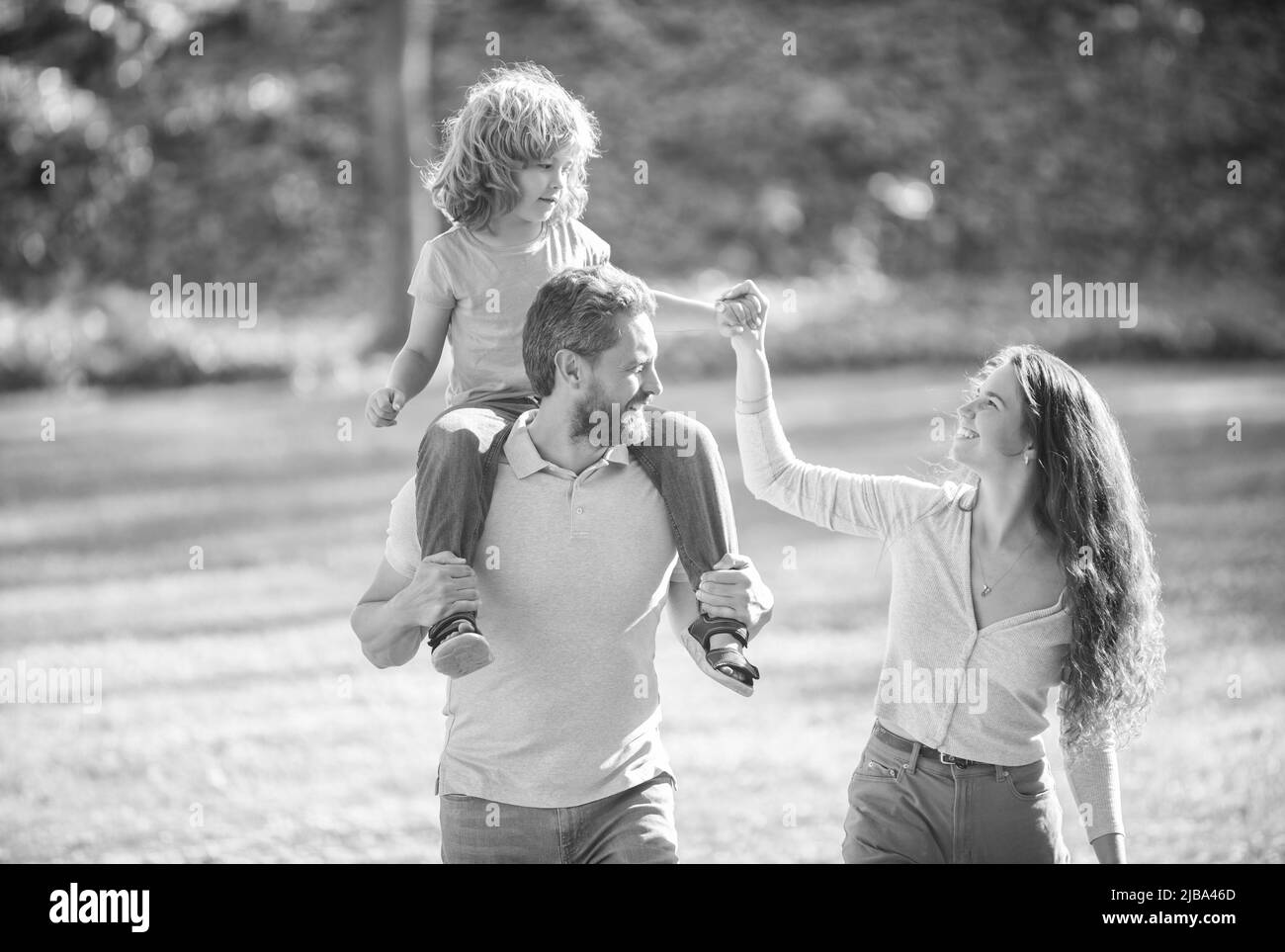 Foster care. Foster parents and son. Mother and child riding piggy back on father. Adoptive family Stock Photo