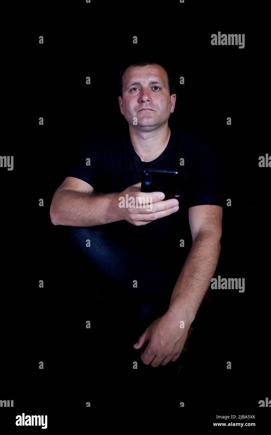 Man with phone on a black background. Stock Photo