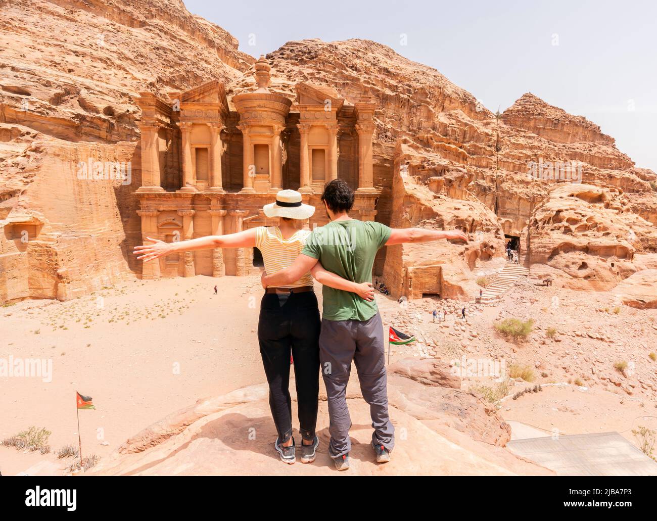 A young couple standing with open arms looking at the monastery of petra - Jordan - travel Stock Photo