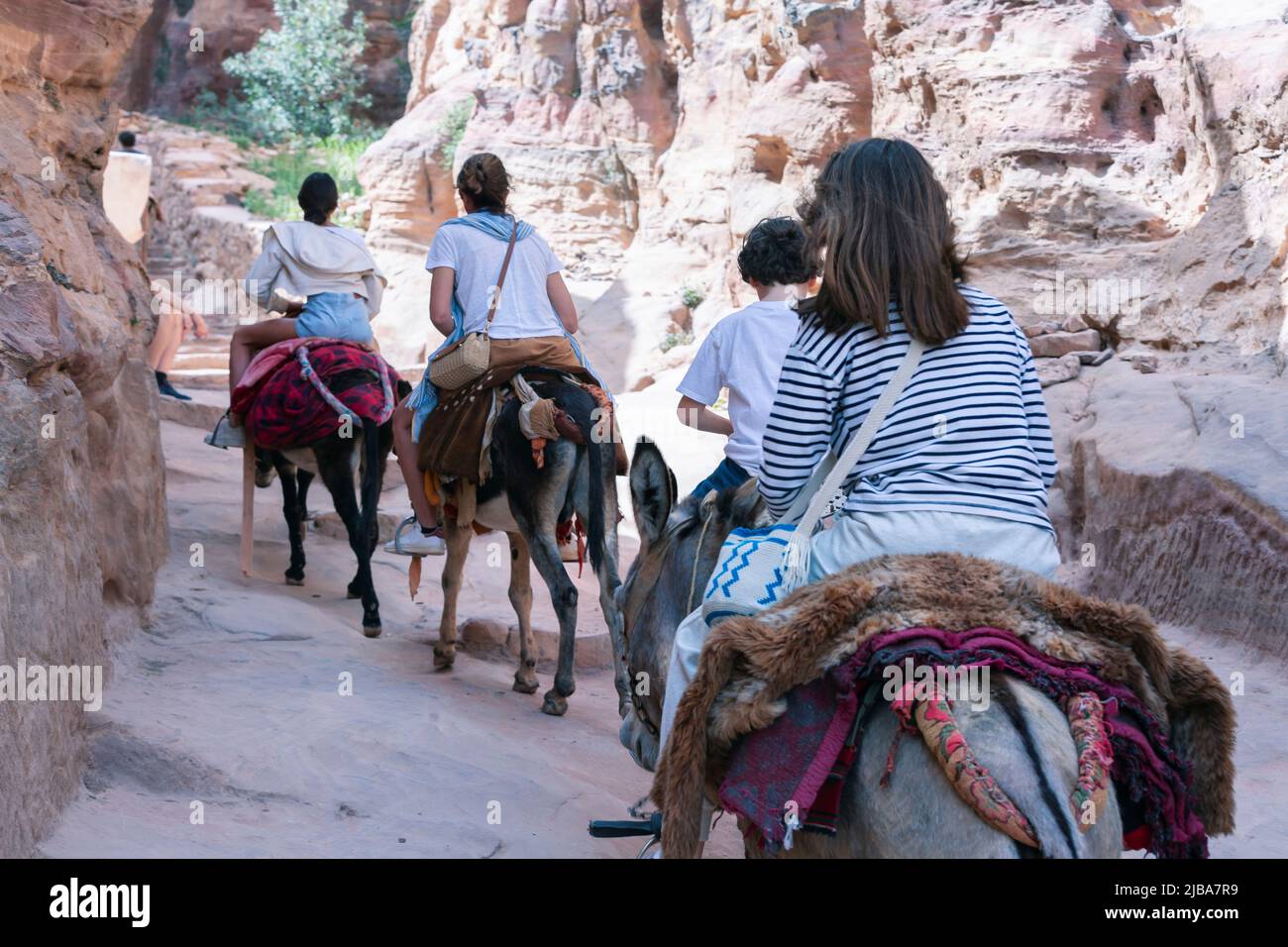 Tourist using a Bedouin donkey for transport in Petra Jordan. Descends stairs next to other tourists walking Stock Photo