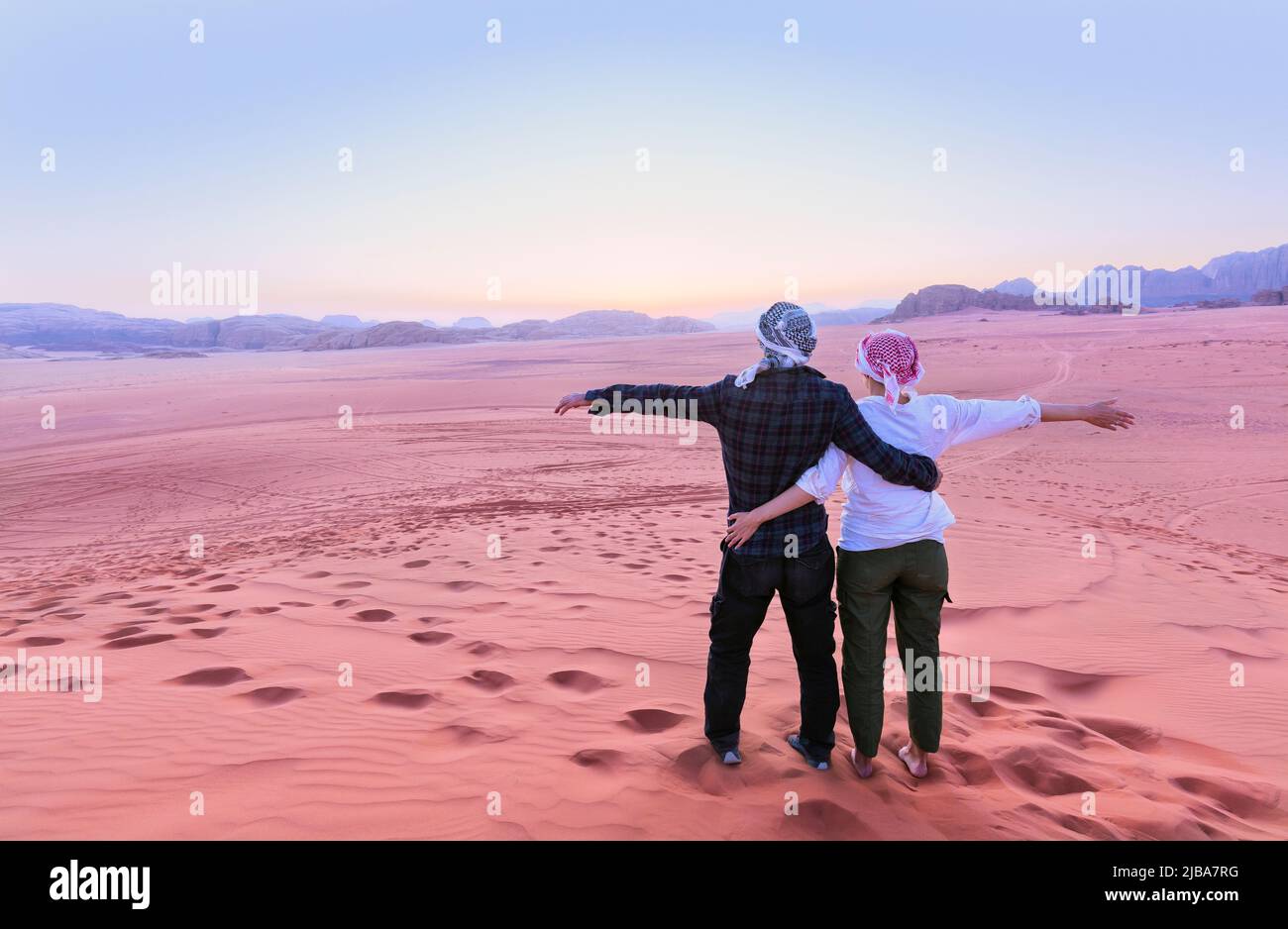 A young couple is watching at sunrise over wadi rum desert in Jordan Stock Photo