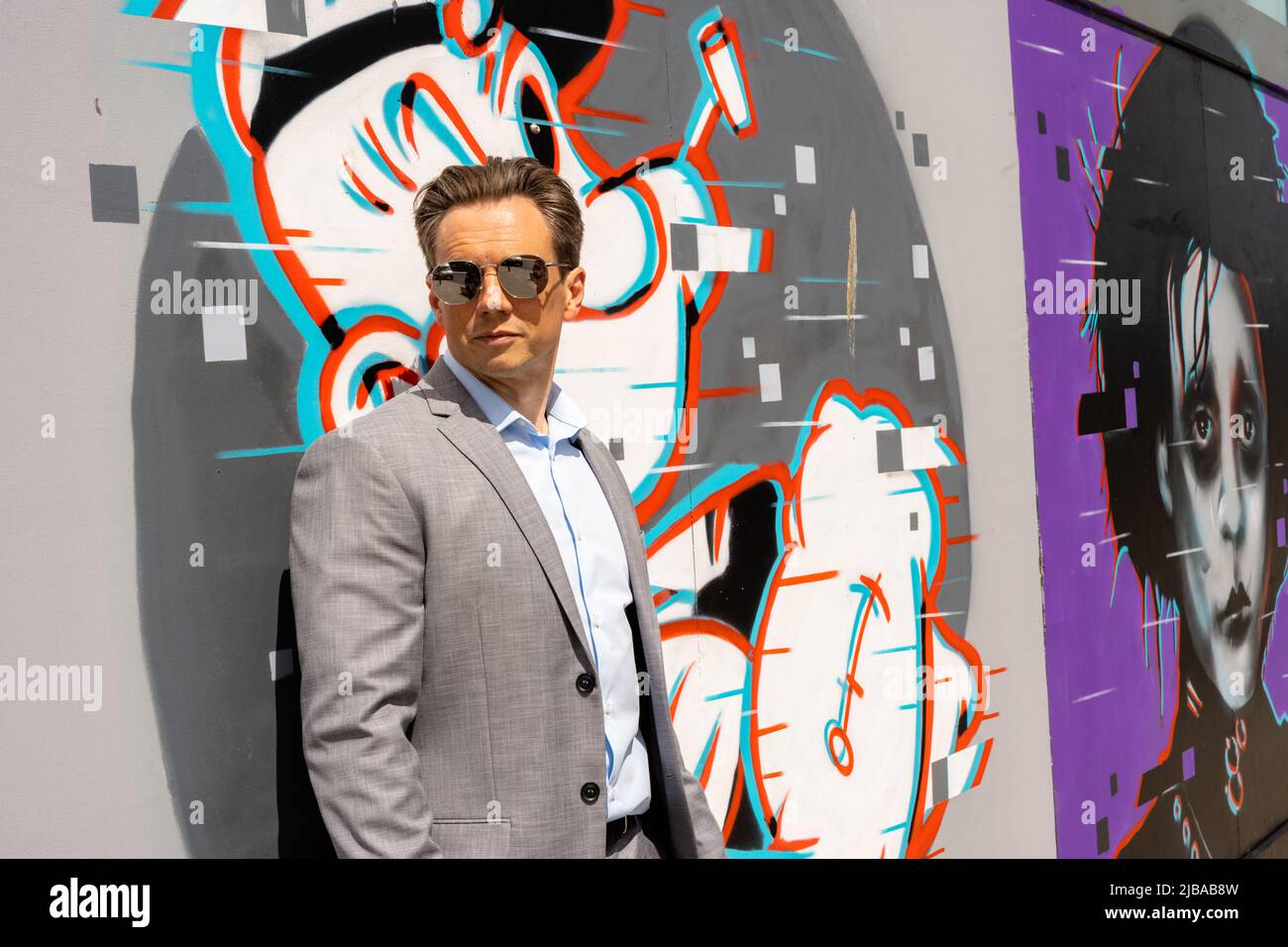 Ipswich Suffolk UK May 27 2022: A handsome businessman in a grey suit in front of some urban artwork Stock Photo