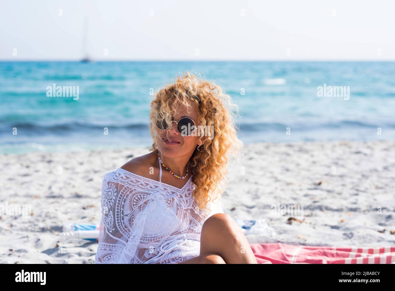 Cheerful female tourist smile and enjoy summer holiday vacation sitting and relaxing at the beach with blue sea water in background. Tropical sand and Stock Photo