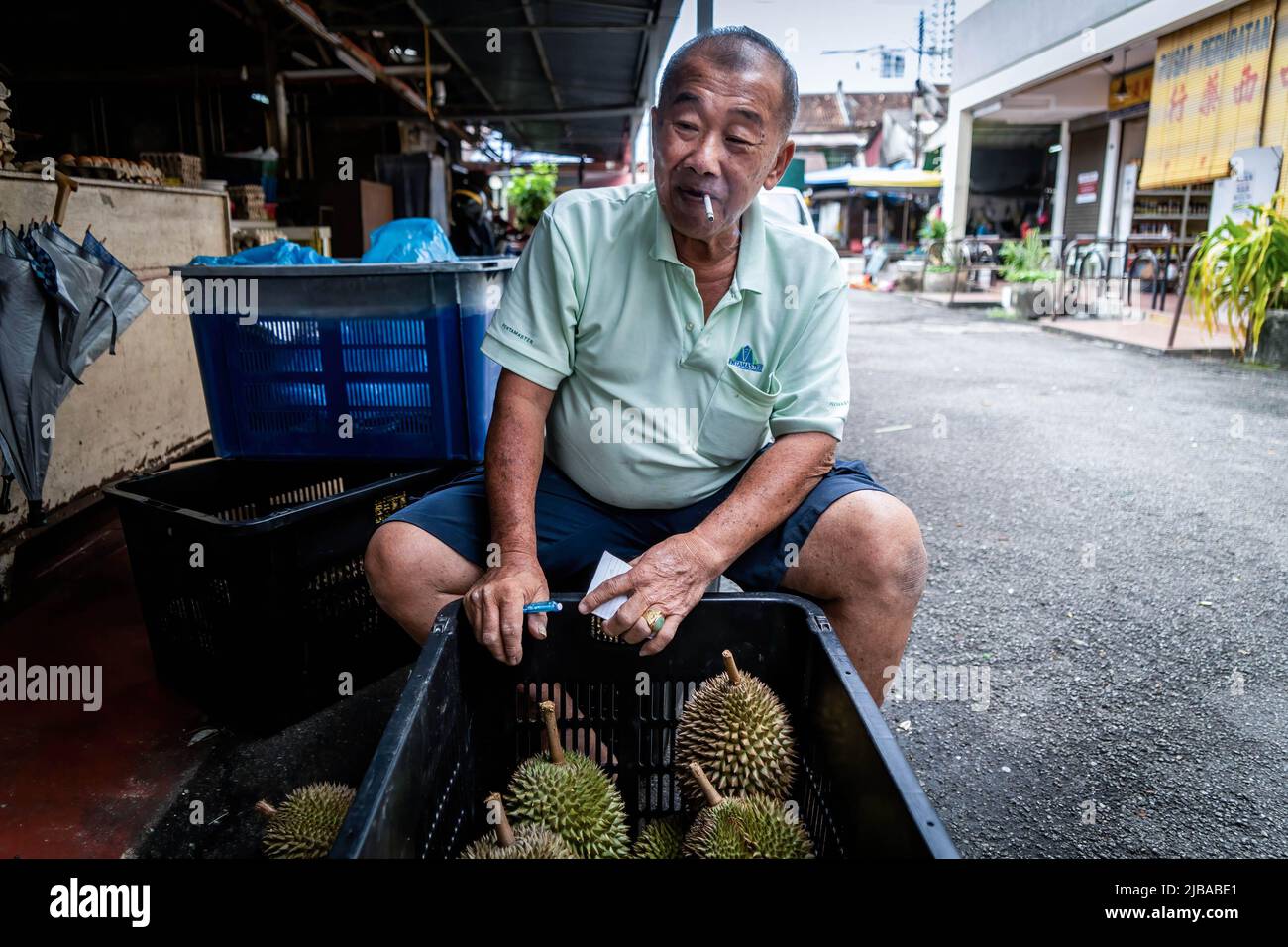 A durian seller smokes a cigarette while negotiating prices for Durian  fruit in George Town, Penang. (Photo by Matt Hunt / SOPA Images/Sipa USA  Stock Photo