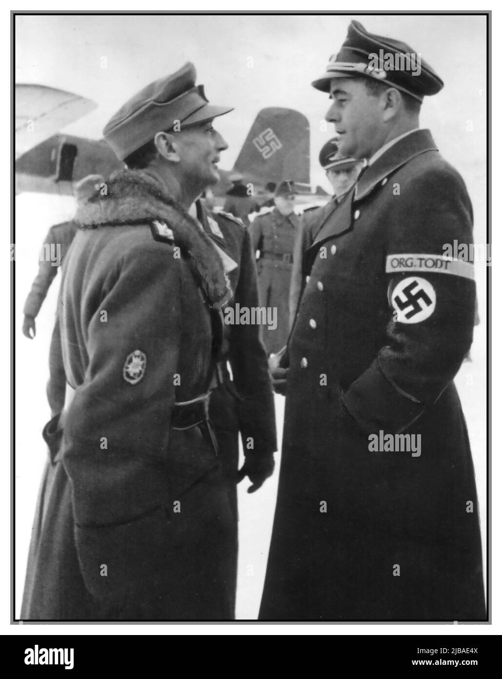 Vintage WW2 Nazi visit to Norway by Albert Speer (right) unusally in military uniform with Swastika armband and General Edward Dietl talking at the field airfield during a front visit to the north of Norway.  Junkers aircraft in background with Swastika symbol on the tail fin of Junkers Aircraft  Albert Speer, Edward Dietl World War II During the German occupation of Norway from 1940 to 1945, Hitler wanted to build an “Aryan” society with gleaming highways and ideal cities. The Nazis wanted to reshape occupied Norway with a remarkable building campaign headed by Speer Date February 1944 Stock Photo