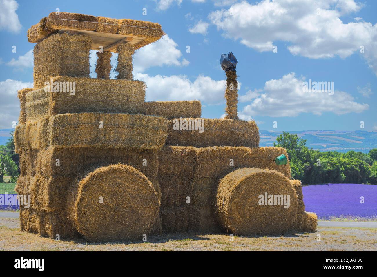 Big hay and straw made tractor for decoration with lavander field in backgroud Stock Photo