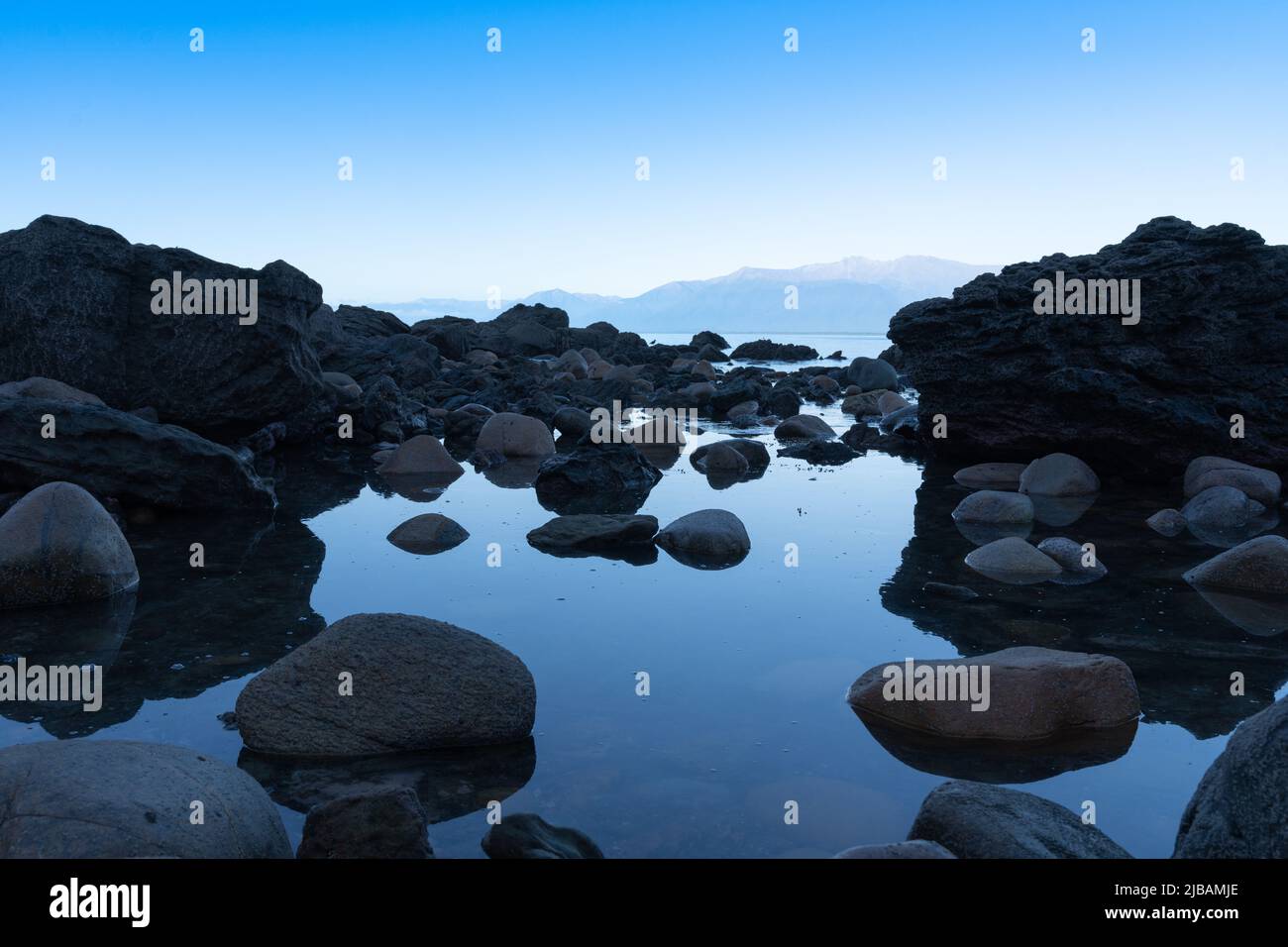 Big round shaped rocks line pool with calm water leading towards ...