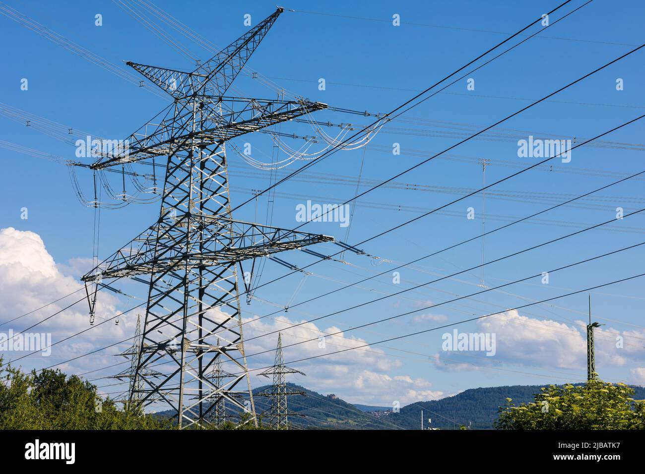 Electrical net of poles on a panorama of blue sky and green meadow. Stock Photo