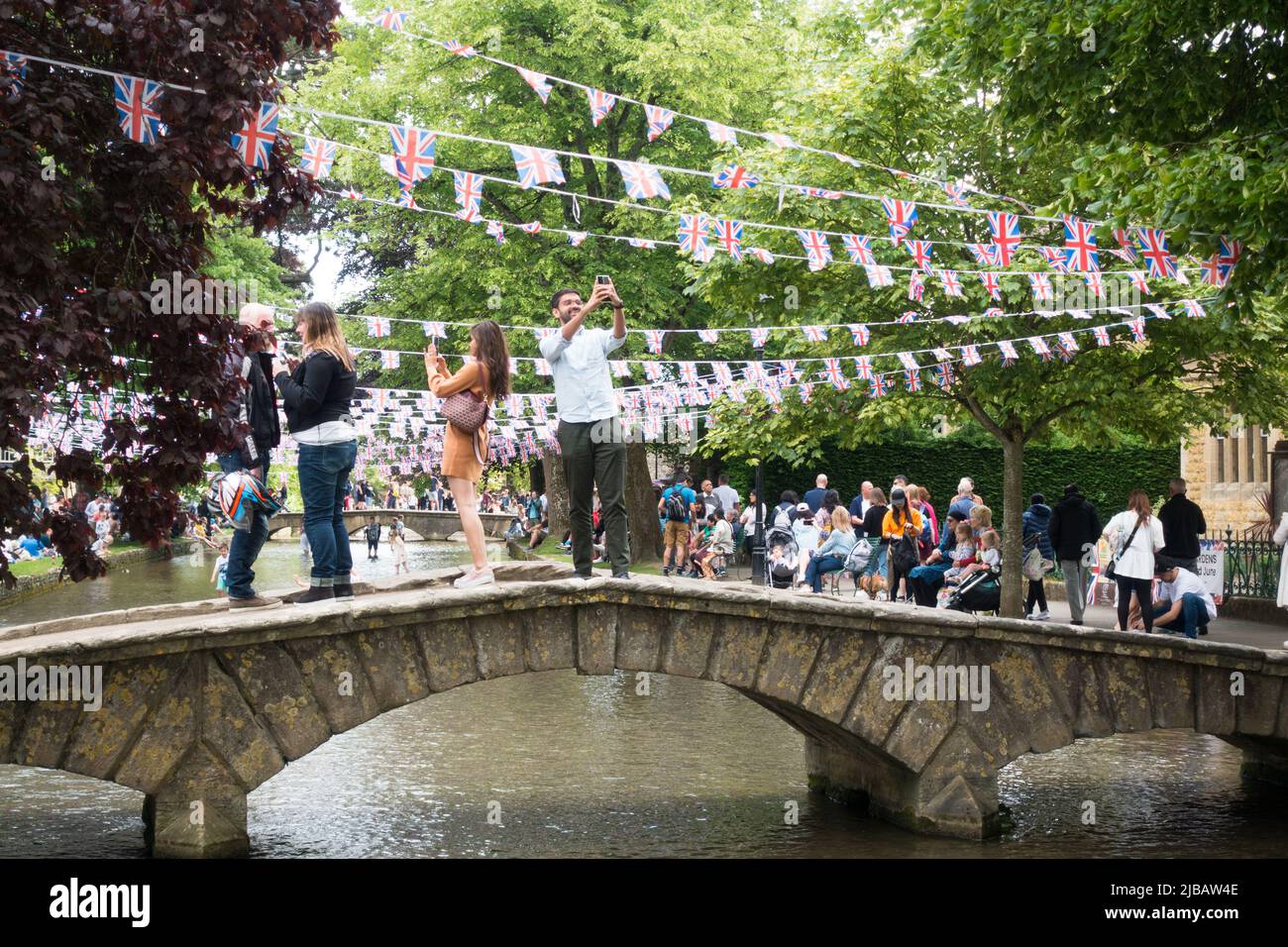 People on low bridges taking selfie over River Windrush in Bourton on water Stock Photo