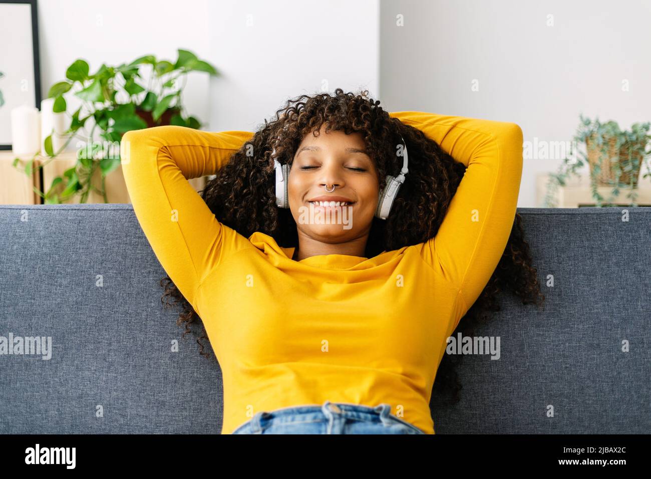 Happy young woman relaxing while sitting on sofa at home Stock Photo