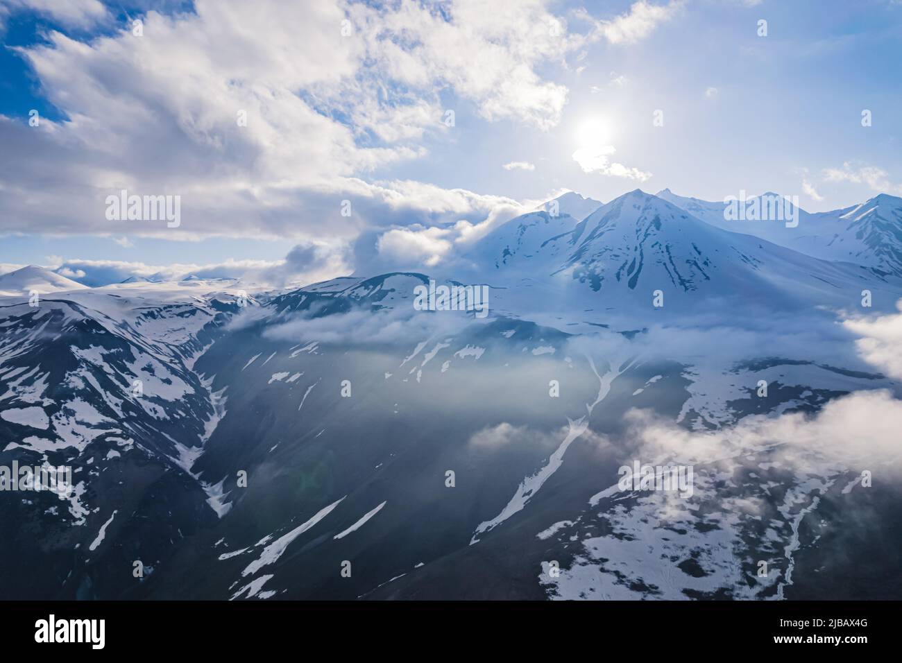 scenic drone shot of wonderful snowy Caucasus mountains in the sunny weather, Kazbegi, Stepantsminda, Georgia. High quality photo Stock Photo