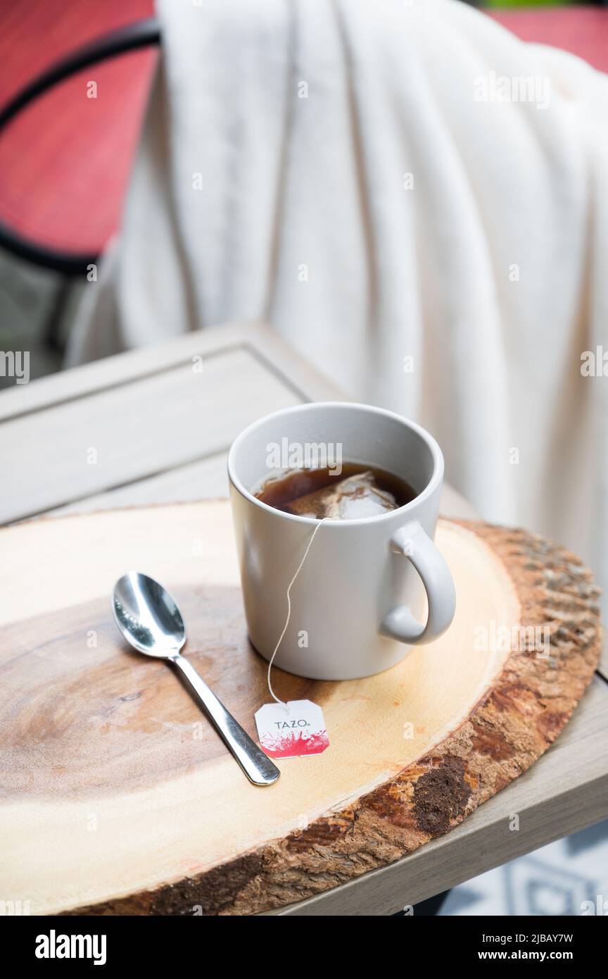 A mug of tea or coffee on a wooden log coffee outdoor patio table at a hotel or Air BnB unit. Stock Photo
