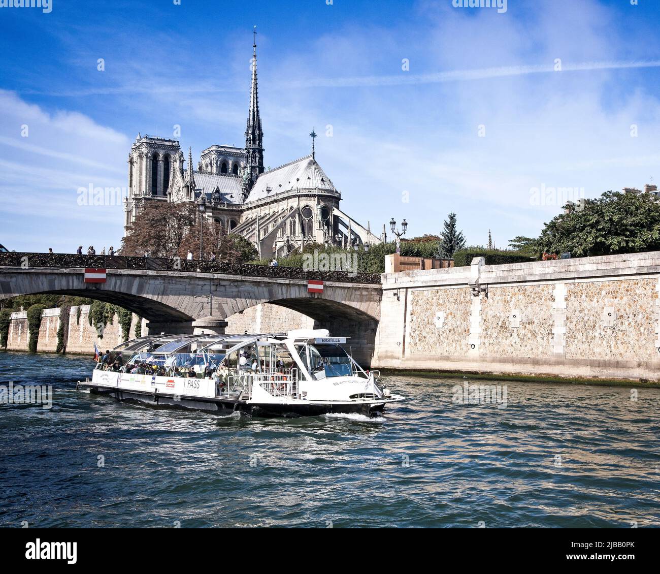 A tourist boat on the River Seine cruises by Notre Dame under the Pont Archeveche bridge.  Paris, France. Stock Photo