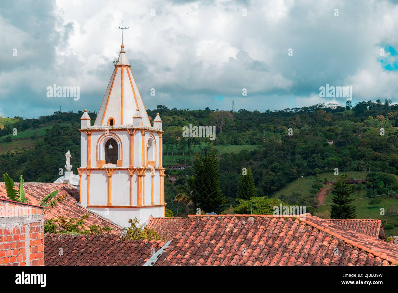 tower of the church of the town of ocamonte in colombia with rooftops and mountain in the background Stock Photo