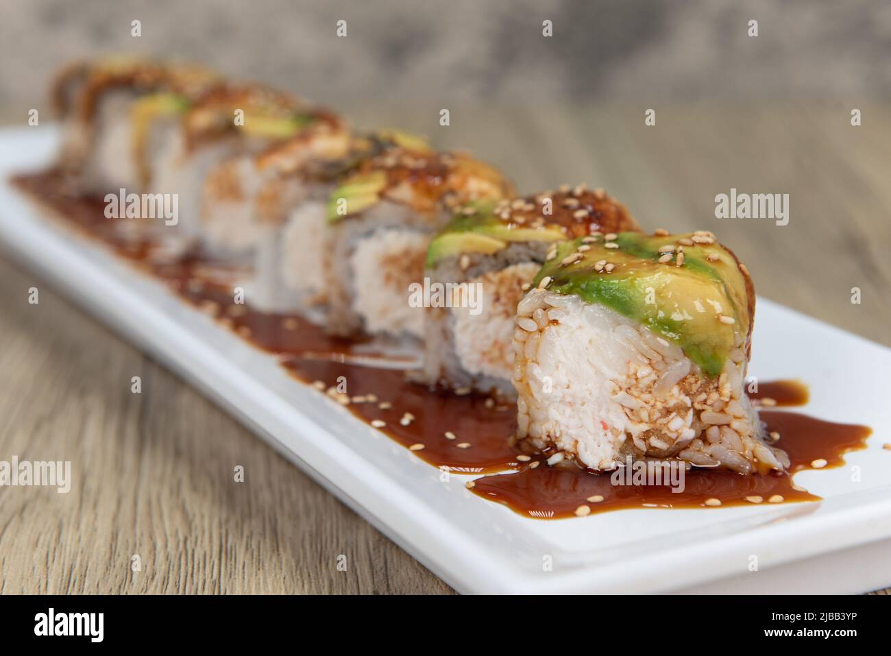 Asian cuisine sushi roll with crab mixed with shrimp tempura and topped with avocado and eel for a very hearty meal. Stock Photo