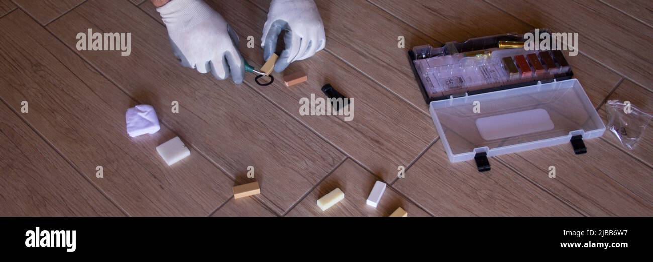 Image of the hands of a handyman repairing a splinter on a tile on the ...