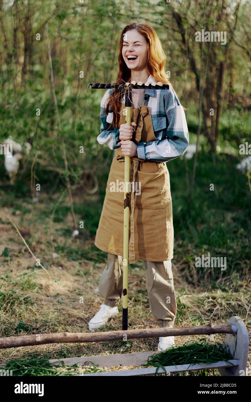 A woman farmer in work clothes and an apron works outdoors in nature