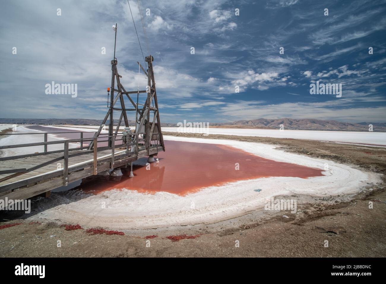 A salt pond with pink water and a wooden platform Stock Photo