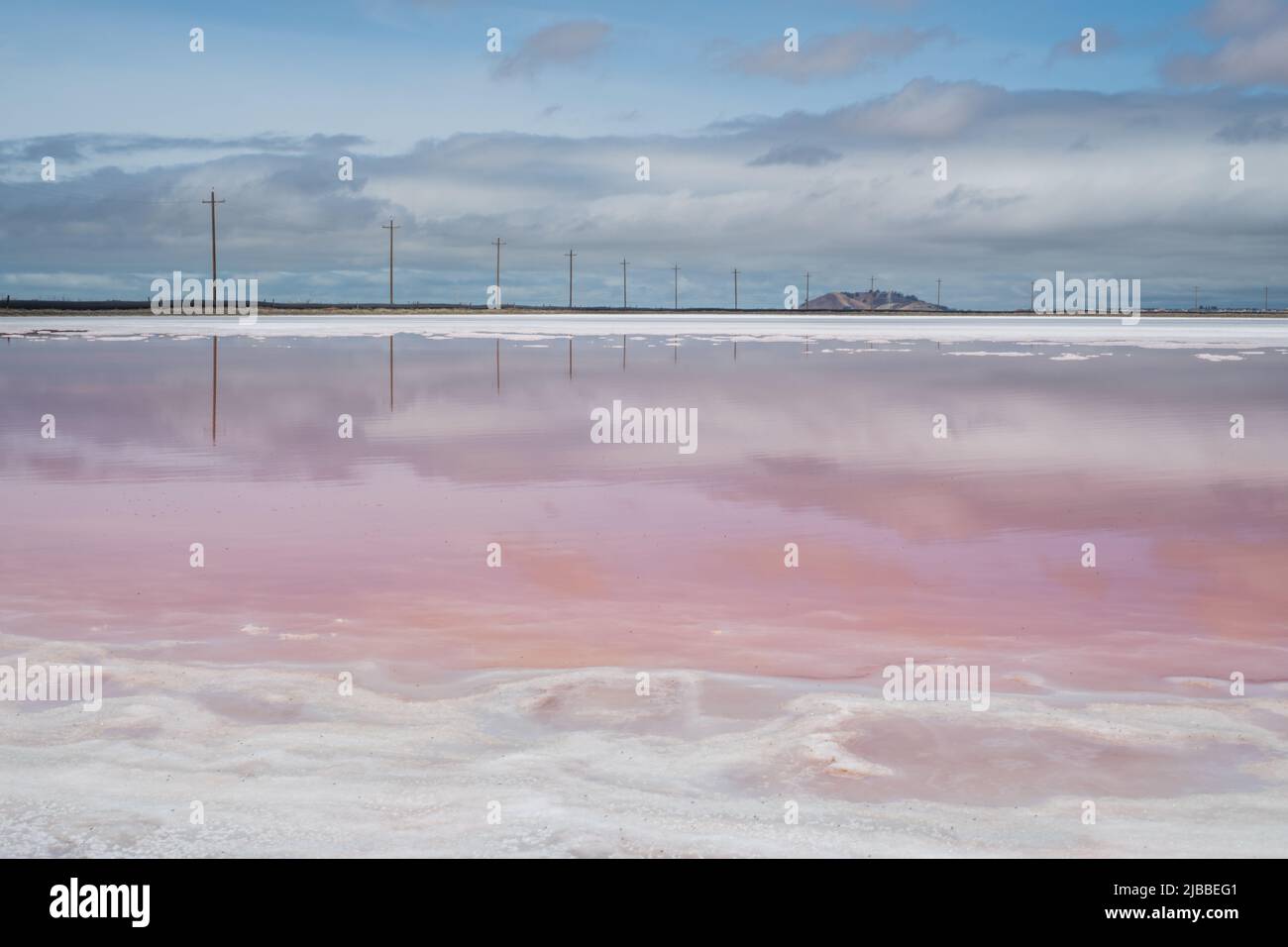 The water in salt ponds takes on a pink hue due to Dunaliella a microorganism creating a beautiful unusual landscape. Stock Photo