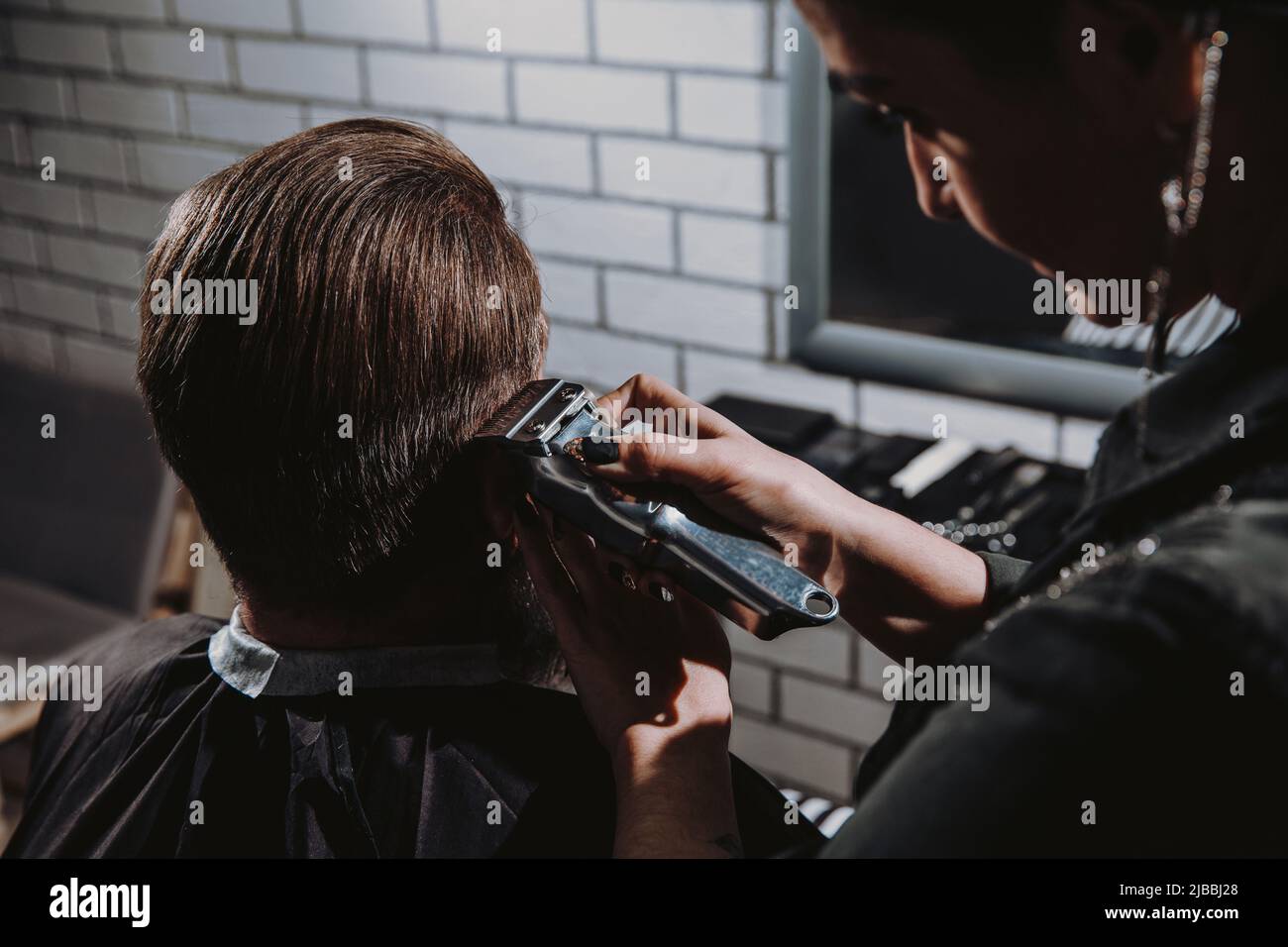 Man getting trendy haircut in barber shop. Stock Photo