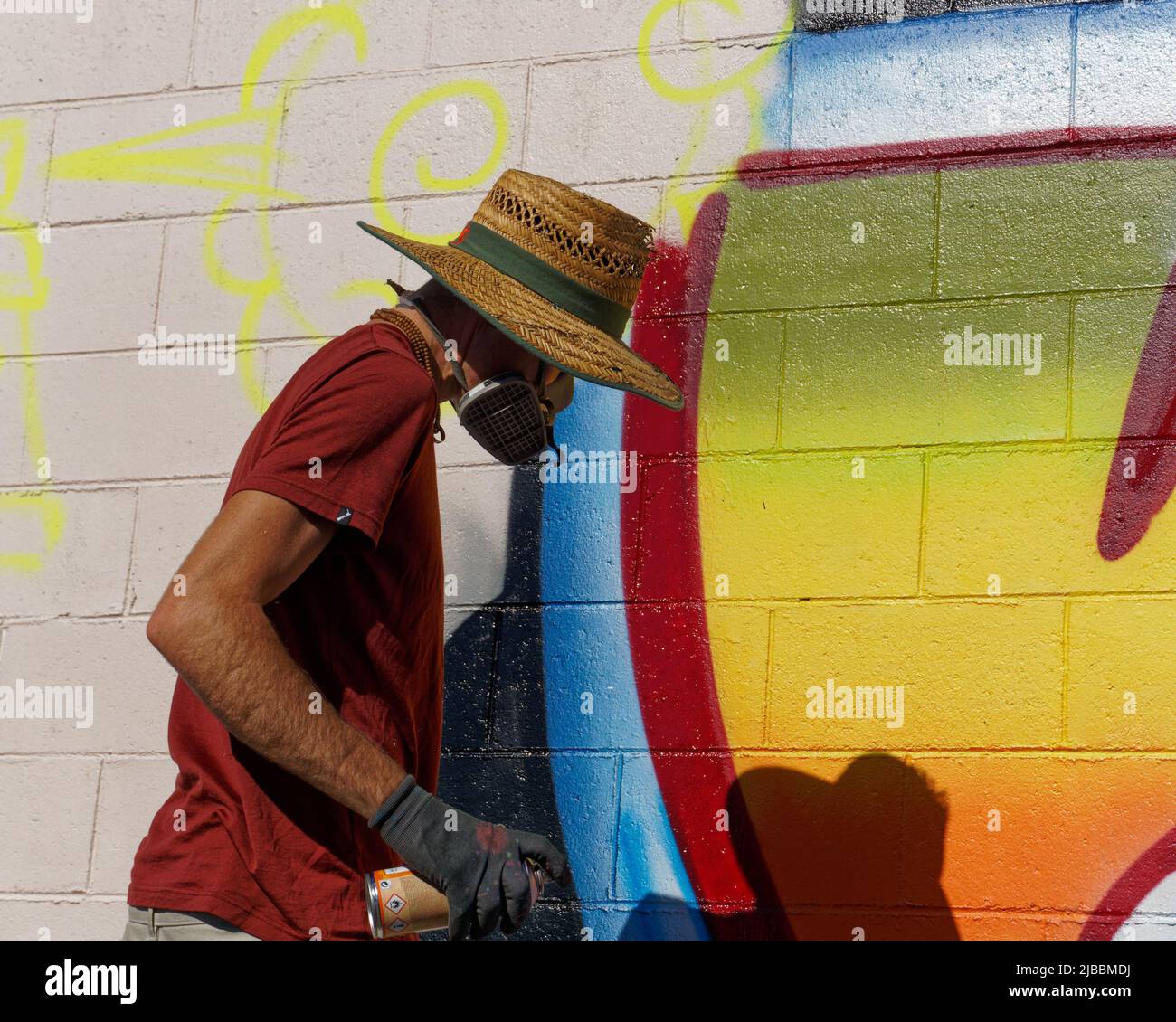 Man painting a mural with spray can paints on a wall in Motueka
