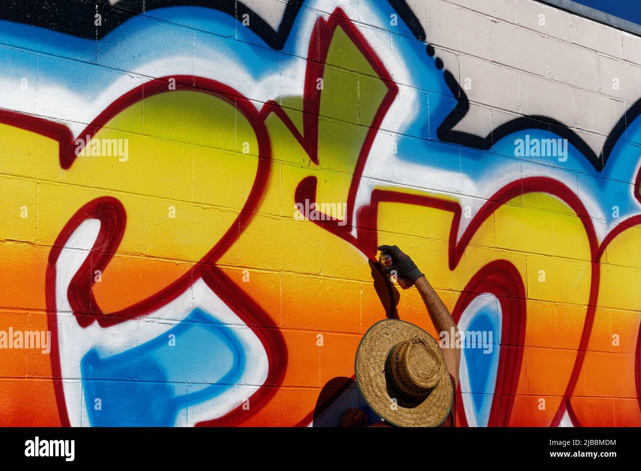 Man painting a mural with spray can paints on a wall in Motueka