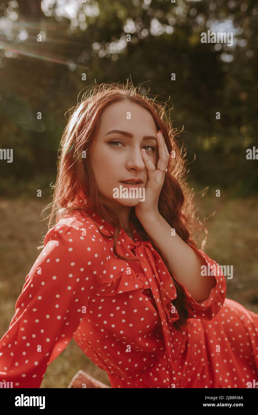 Redhead woman posing on a camera outdoor on the dry grass field on the ...
