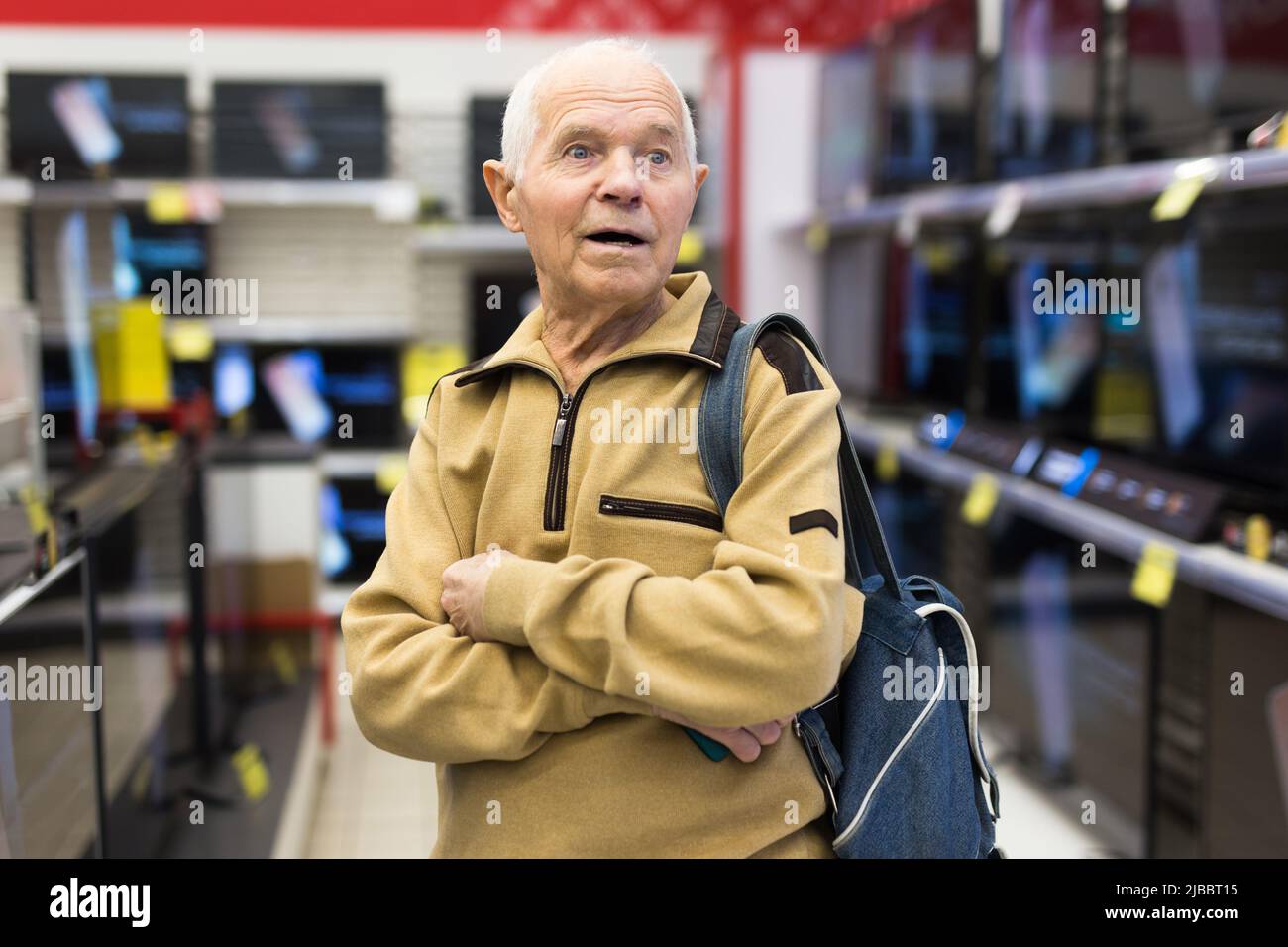elderly man choosing TV in showroom of electronics store Stock Photo