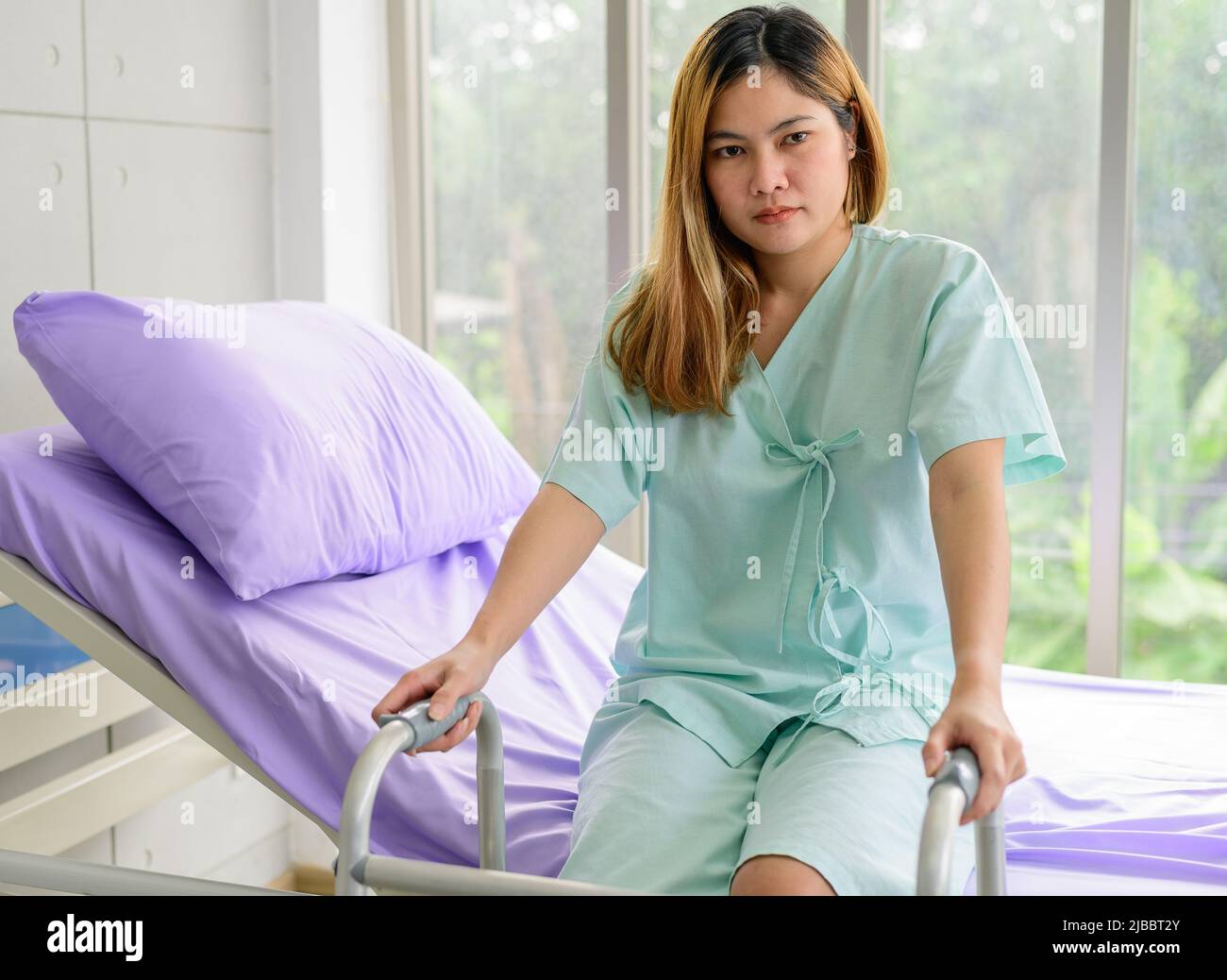 Young asian woman with walking frame stand up from bed at hospital Stock Photo